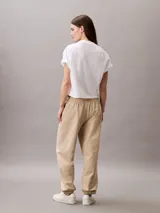 Pantalón jogger Calvin Klein de felpa color beige, con cintura elástica, bolsillos laterales y bajos de canalé. Cuenta con el monograma CK bordado en la pierna.