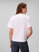 Remera Calvin Klein de algodón color blanco, con cuello redondo, mangas cortas y estampa frontal cuadrada con el monograma cK en tonos degradados de rojo y rosado.