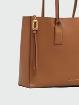Cartera tipo tote bag Marc Jacobs The Puffy J Marc Work Tote, color negro con herrajes dorados y logotipo de la marca impreso en el frente.