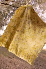 Pañuelo rectangular de tela fina color crema con estampado artesanal de hojas y flores en tonos amarillos y marrones.