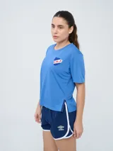 Remera de fútbol Umbro del Club Nacional de Football, modelo Bink para mujer. Diseño azul oscuro con cuello redondo y mangas cortas, con logo de Umbro en el pecho derecho y escudo del club en el pecho izquierdo.