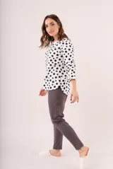 Pijama de dos piezas, compuesto por una remera de manga larga blanca con lunares negros y un pantalón largo gris.