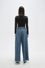 Pantalon de jean negro de corte ancho y tiro alto, con detalle de estrella bordada en la pierna y ruedo deshilachado.