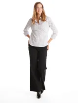 Camisa entallada de algodón con estampado de rayas verticales en tonos blanco y gris. Presenta cuello con solapa, escote en V, cierre frontal con botones y mangas tres cuartos con puños anchos. El diseño incluye paneles laterales elastizados para un ajuste flexible y ruedo redondeado.