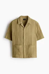 Camisa de manga corta H&M con cuello resort, cierre frontal de botones y bolsillos frontales aplicados. Confeccionada en tejido texturizado de corte relajado.