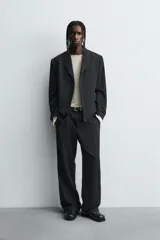 Pantalón de corte relaxed fit confeccionado en tejido con mezcla de lana, con bolsillos delanteros y traseros de vivo, cierre frontal con cremallera y botón.
