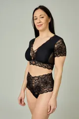 Conjunto de lencería negro compuesto por un bralette de lycra y microtul con detalles de encaje en escote, bajo busto y mangas cortas, y una bombacha hipster de tiro alto confeccionada íntegramente en encaje.