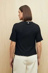 Top negro de textura acanalada con cuello semi alto y mangas largas. Presenta un diseño ajustado al cuerpo con una sutil abertura lateral en el ruedo.