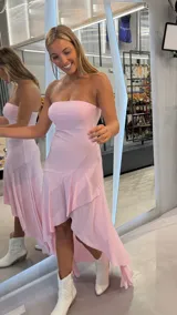 Vestido largo rosado con brillo, strapless y diseño asimétrico con volados en la parte inferior.