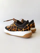 Championes deportivos de cuero con estampado animal print, cordones marrones y suela blanca con base color caramelo.