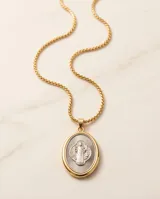 Collar de cadena de eslabones con baño de oro y dije ovalado colgante con relieve de San Benito en tono plateado y borde dorado.