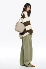 Bolso bandolera de tamaño pequeño, confeccionado en poliamida con detalles en piel vacuna. Cuenta con asa regulable de tejido, cierre con cremallera, bolsillo interior y logo de la marca estampado en la parte frontal.