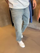 Jean de corte mom en color azul claro con efecto lavado, confeccionado en denim de alta calidad, con diseño de cinco bolsillos y cierre frontal.