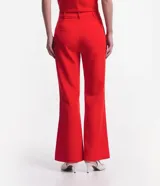 Pantalón flare de sastrería color rojo, con cintura alta, trabillas y cierre cruzado con botones.