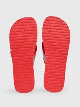 Ojotas rojas con suela texturizada y tira plateada con logo de Calvin Klein Jeans.