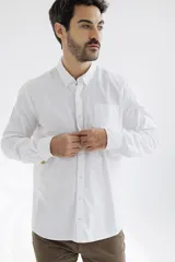 Camisa blanca de corte clásico, confeccionada en tela Oxford con cuello abotonado, manga larga y bolsillo en el pecho.