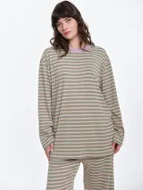 Remera de dormir oversize con estampado de rayas horizontales en tonos verde, rosa y beige. Presenta cuello redondo en color lila y mangas largas.