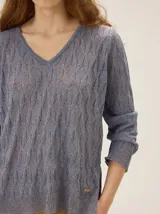 Buzo de tejido en lurex con escote en V, manga larga y silueta relajada, con un brillo sutil y textura tramada.