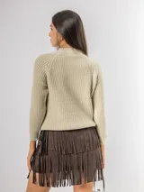 Sweater de punto color beige con diseño de ochos en el frente y mangas raglán. Presenta cuello redondo alto y puños acanalados.