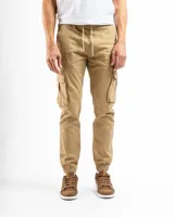 Pantalón cargo tipo jogger en color beige, confeccionado en tejido de algodón con spandex. Presenta un diseño funcional con múltiples bolsillos laterales con solapa, cintura ajustable con cordón y puños elásticos en los tobillos.