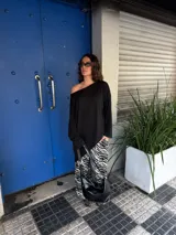 Conjunto de buzo asimétrico de manga larga con hombro descubierto y pantalón tiro alto de pierna ancha con estampado animal print tipo cebra, confeccionados en viscosa.