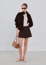 Minifalda marrón oscuro de corte recto, con diseño liso y cierre cruzado simulado.