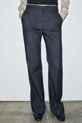 Jeans de tiro medio con corte flare y largo completo. Presenta bolsillos delanteros, cierre con cremallera, botón y ganchos metálicos.
