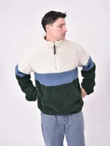 Buzo de polar tipo sherpa con diseño tricolor en bloques, cuello alto con cierre frontal parcial y bolsillo tipo canguro frontal.