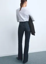 Jeans de tiro medio con diseño flare y bajo deshilachado, confeccionados en tejido elástico de algodón estilo denim. Presentan cinco bolsillos, trabillas y cierre delantero con cremallera y botón.