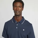 Remera polo azul marino de piqué de algodón, con cuello clásico con ribete blanco, tapeta de dos botones y mangas cortas con ribete blanco.