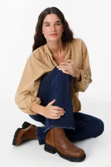 Bota de cuero color suela con diseño chunky, punta cuadrada y suela de goma dentada en color negro. Presenta costuras visibles en el empeine y cierre lateral.