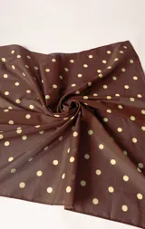 Pañuelo de tela color marrón con estampado de lunares beige.