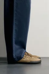Zapatilla deportiva barefoot de hombre, confeccionada en piel con acabado serraje de color marrón, puntera redondeada, suela fina de goma oscura y detalles en cuero liso en el talón.