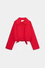Chaqueta corta roja ZARA Woman Collection con mezcla de algodón, cuello alto, manga larga, bolsillos delanteros y cinturón ajustable con lazada en el mismo tejido. Cuenta con cierre frontal con botones ocultos por solapa.