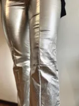 Pantalón plateado de corte recto con aberturas en el ruedo.