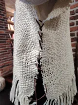Ruana de lana color crudo, tejida a mano con diseño calado y flecos largos en el ruedo.
