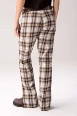 Pantalón de tiro medio con diseño de cuadros tartán en tonos marrón, blanco y negro, combinado con detalles de cuero en la parte superior y grandes bolsillos frontales.