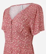 Enterito corto color rosa con estampado floral, escote en pico, botones y mangas cortas holgadas.