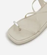 Sandalia tipo flatform color beige, con diseño de tiras finas, dedal metálico en la parte frontal y cierre con hebilla en el talón. Suela plana de altura media.