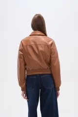 Chaqueta estilo bomber corta de eco-cuero color caramelo, con cuello camisa, cierre frontal de botones oscuros y puños y cintura de tejido acanalado.