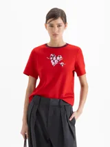 Remera de jersey pesado color rojo, con cuello redondo en contraste color bordó y estampa frontal de un corazón con flecha. Presenta mangas cortas y corte recto.