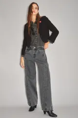 Jean de corte wide leg en color gris oscuro con efecto lavado. Presenta costuras verticales decorativas a lo largo de las piernas y cierre frontal con botón y cremallera.