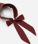 Visera de playa para mujer confeccionada en fibra de papel con textura trenzada. Presenta un diseño de ala ancha y un lazo de tela largo en la parte posterior para anudar.