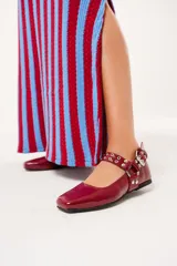 Balerinas color borgoña de charol con punta cuadrada, correa con hebilla y apliques metálicos.