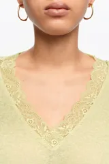 Jersey corto de corte recto confeccionado en mezcla de lino y algodón. Presenta un escote en V pronunciado con detalle de encaje al tono y mangas largas con caída holgada.
