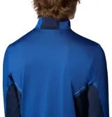 Remera de manga larga Columbia con tecnología Omni-Wick, diseñada para actividades deportivas. Presenta cuello con media cremallera, paneles laterales en tono azul más oscuro, orificios para los pulgares en los puños y detalles reflectantes.