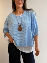 Buzo celeste de tejido calado con diseño oversize, cuello redondo y mangas tres cuartos.