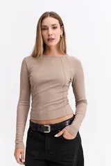Remera de manga larga color beige, con ajuste al cuerpo y costuras decorativas visibles en el frente que realzan la silueta.