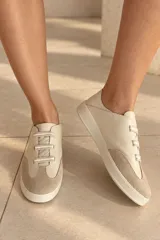 Championes de cuero vacuno color celeste con puntera de gamuza marrón, suela de goma y cordones elásticos.
