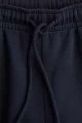 Pantalón de jogging azul marino de felpa con interior cepillado suave. Presenta cintura elástica fruncida con cordón ajustable, bolsillos laterales discretos y elástico revestido en los bajos.